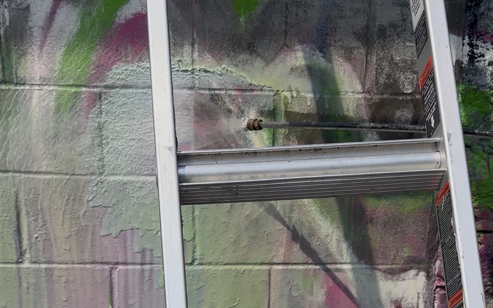 Grit & Grind removing graffiti from a block wall