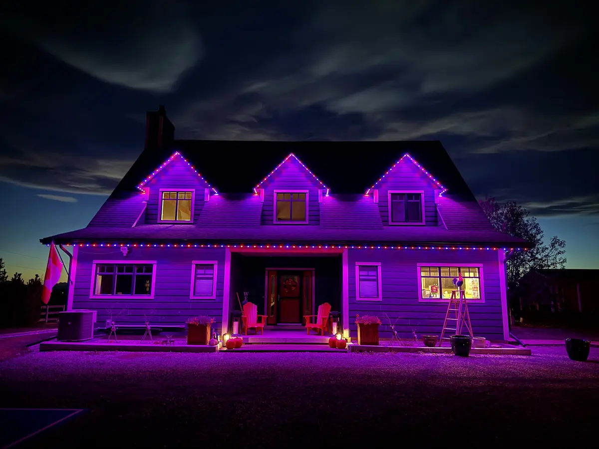 Farmhouse with three dormers lit purple by permanent lights
